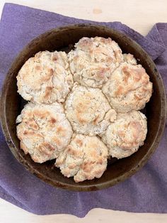 a brown bowl filled with biscuits on top of a purple table cloth next to a knife and fork