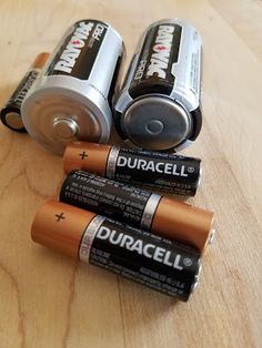 three batteries are sitting on a wooden table