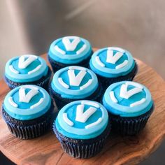 cupcakes with blue frosting and white letters on them sitting on a wooden plate