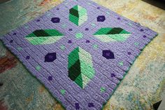 a purple crocheted square with green leaves on it sitting on top of a table