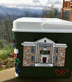 a cooler sitting on the side of a road with mountains in the backgroud