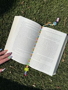 a person is holding an open book in their hand with beads on it and a beaded bracelet