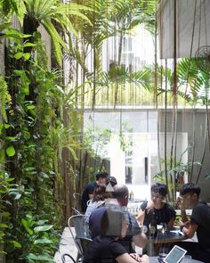 people sitting at tables in an outdoor restaurant with plants growing on the walls and ceiling