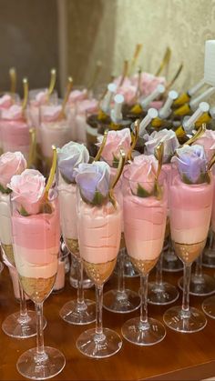 there are many glasses that have pink and purple flowers in them on the table together