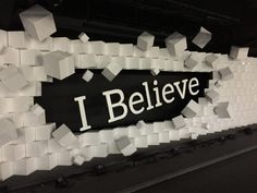 a black and white sign that says i believe surrounded by lots of cubes on the wall