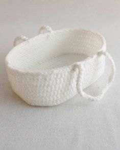 a white crocheted basket on a white tablecloth with two strings attached to it