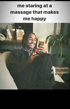 a man sitting on a couch holding a cell phone in his hand and smiling at the camera