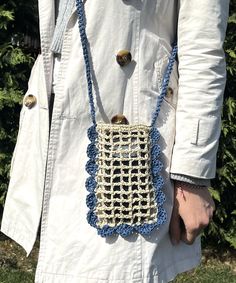 a woman is holding a crocheted purse in her hands while wearing a white coat