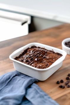 two white dishes filled with chocolate cake on top of a wooden table next to blue napkins