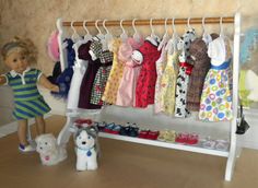 a doll is standing next to a rack with clothes