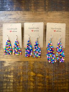 three pairs of colorful beaded earrings sitting on top of a wooden table next to each other