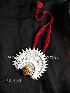 a white and red decoration on top of a black cloth with the word paas - deh written below it