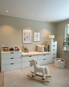 a white rocking horse in a room with beige walls and carpeted flooring on the floor