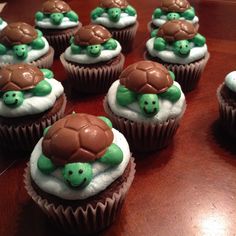 cupcakes with green and brown decorations on top of a wooden table in the shape of turtles