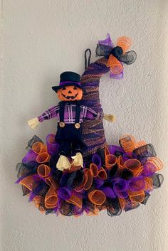 a scarecrow hanging on the wall with purple and orange tulle skirted net