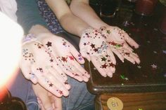 two hands with stars painted on them are sitting next to each other at a table