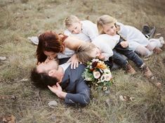 a family laying in the grass with their heads on each other's chests