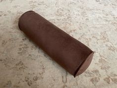 a roll of toilet paper sitting on top of a carpet covered in brown fabric next to a rug