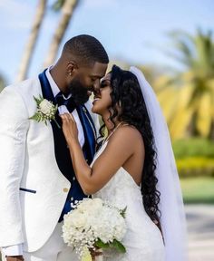 a bride and groom kissing in front of palm trees