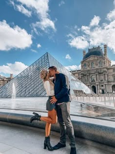 a man and woman kissing in front of the pyramid