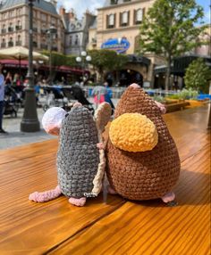 two crocheted mice sitting on top of a wooden table next to each other