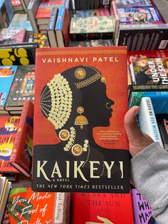 a person holding up a book in front of bookshelves