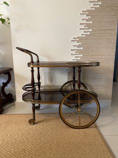 an old fashioned bar cart sitting on top of a rug in front of a wall