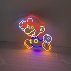 a neon sign that has a nintendo mario on it's face and is lit up in the dark