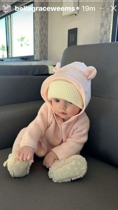 a baby is sitting on the couch wearing a hat