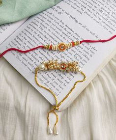 two bracelets on top of an open book with beads and pearls hanging from it