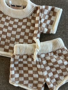 The perfect transition piece for Fall! Hand-knit cotton/polyester blend into a checkered, two-piece set. A neutral, unisex option that both mamas and babes will love! Casual Cotton Gingham Sets, Casual Gingham Cotton Sets, Cozy Playtime Sets For Fall, Cozy Cotton Sets For Fall, Plaid Cotton Playtime Set, Cute Plaid Cotton Sets, Playful Brown Cotton Sets, Cute Plaid Playtime Sets, Short Set