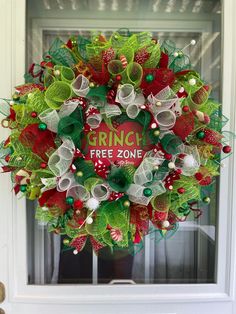 a christmas wreath with green and red decorations hanging on the front door to give it a festive feel