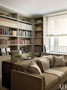 a living room filled with furniture and bookshelves next to a window covered in lots of books