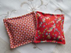 two red pillows sitting on top of a bed next to each other