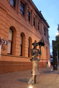 there is a statue on the sidewalk in front of a building