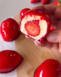 someone is holding a piece of fruit with cream and strawberries in the background on a cutting board