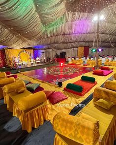 an indoor dance floor is decorated with bright colors and draping on the ceiling