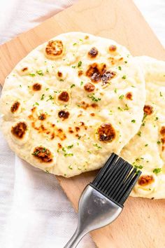 two flat breads on a cutting board with a brush