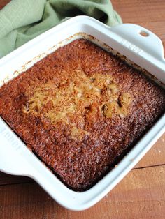 a cake in a white dish on a wooden table