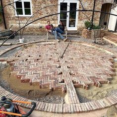 two people sitting on a bench in the middle of a brick patio