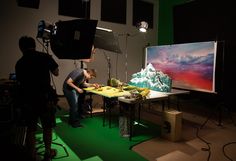 two people are preparing food in front of a large screen on a green carpeted floor