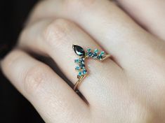 a woman's hand wearing a ring with blue stones on the side and a gold band