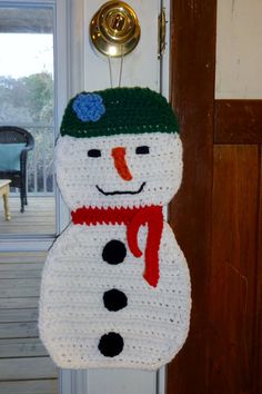 a crocheted snowman ornament hanging from a door