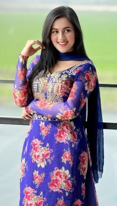 a woman in a blue and red dress posing for the camera with her hands on her hips