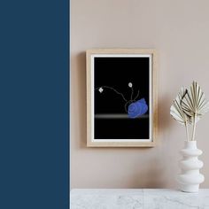 a white vase with flowers in it next to a black and white photograph on the wall