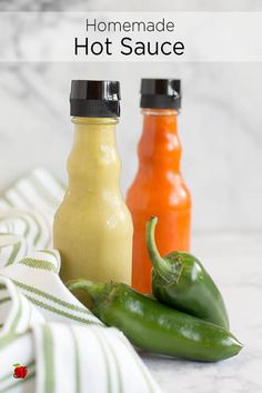 three bottles of hot sauce sitting on top of a counter next to peppers and jalapenos