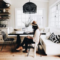 a woman sitting at a table in front of a window with a laptop on it