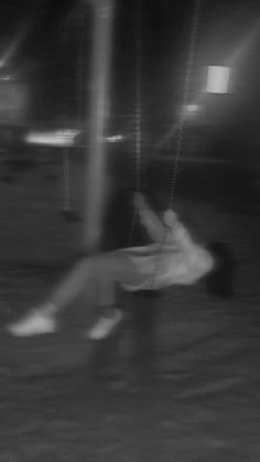 black and white photograph of a woman swinging on a swing