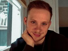 a young man is posing for the camera with his hand on his chin and looking at the camera