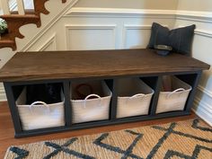 an entryway bench with storage baskets underneath it and stairs in the backround